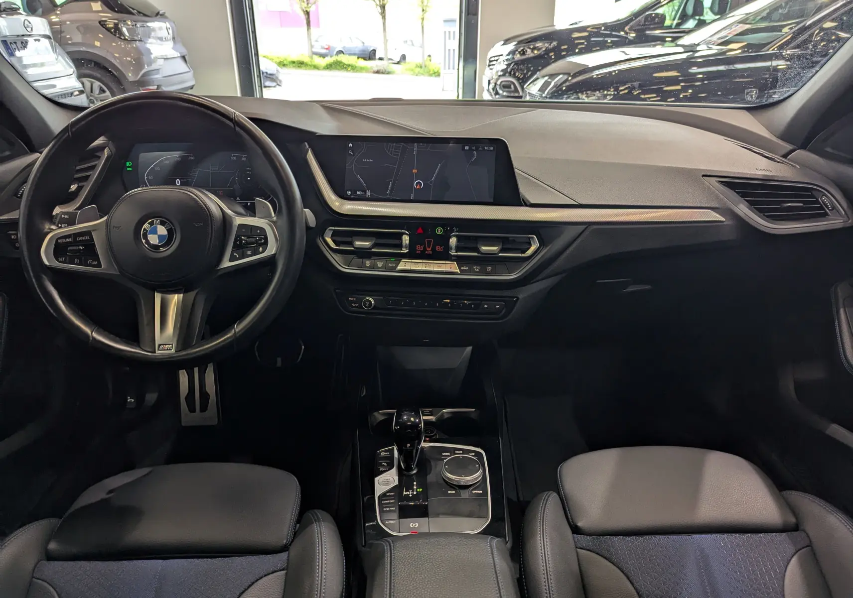 Intérieur noir de la BMW Série 1 F40 18d 2023, vue frontale du tableau de bord avec écran central et volant M Sport.