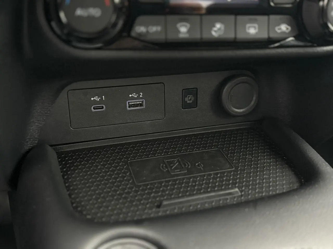 Gros plan sur la console centrale du Nissan Juke blanc nacré 2025, montrant ports USB et chargeur sans fil.