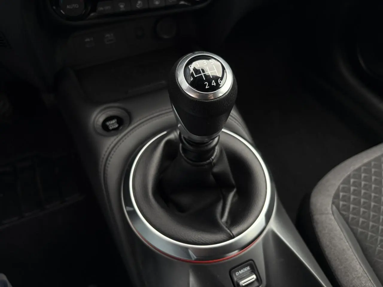 Gros plan sur le levier de vitesse manuel noir du Nissan Juke 2025, entouré d’un habillage argenté et cuir noir.
