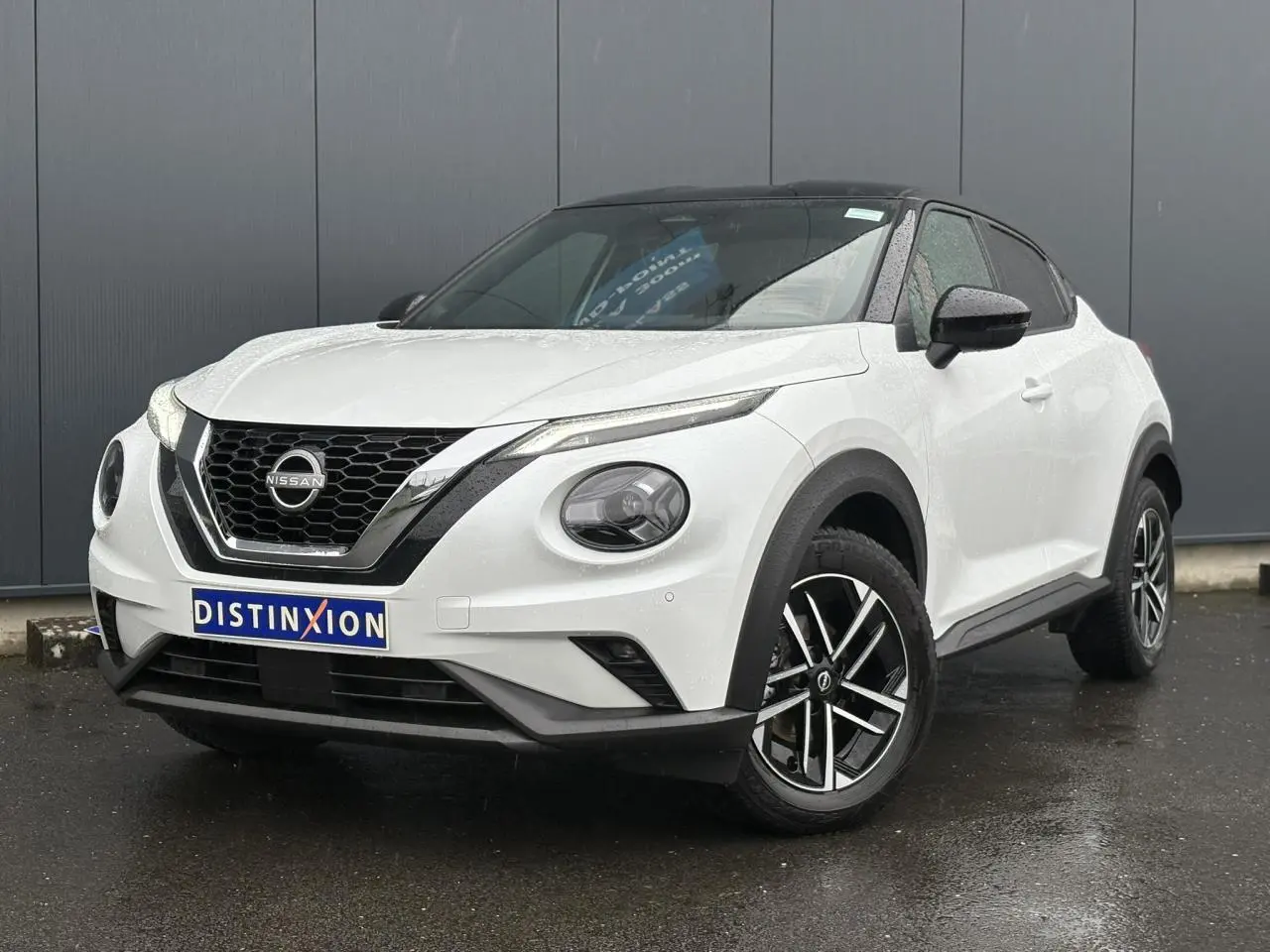 Nissan Juke blanc nacré en 3/4 avant droit, avec toit noir et jantes alliage 17 pouces au design moderne.