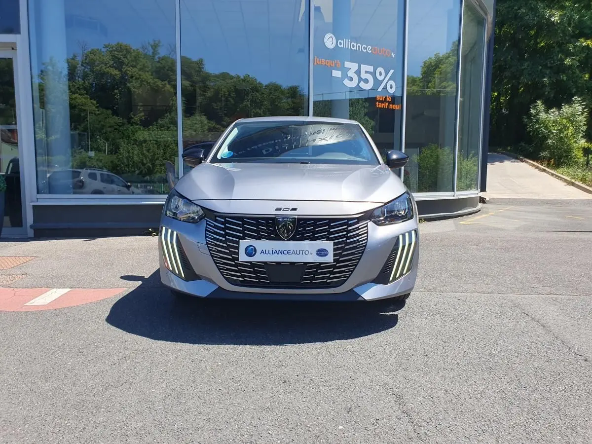 Vue frontale d'une Peugeot 208 gris Artense avec calandre noire et feux diurnes LED en griffes.