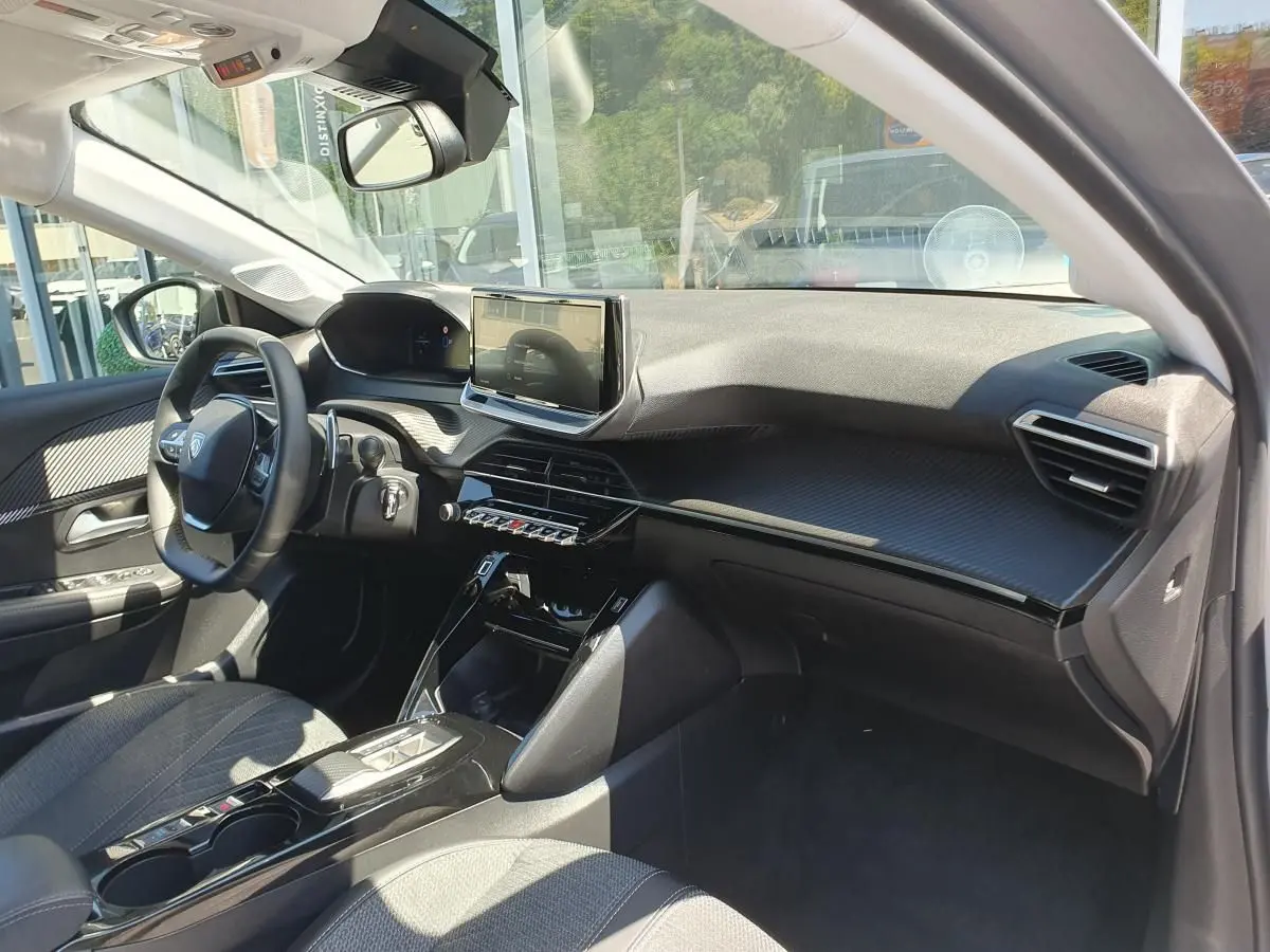 Intérieur avant droit de la Peugeot 208 1.2 Hybrid 110 gris Artense, avec tableau de bord moderne et écran tactile central.