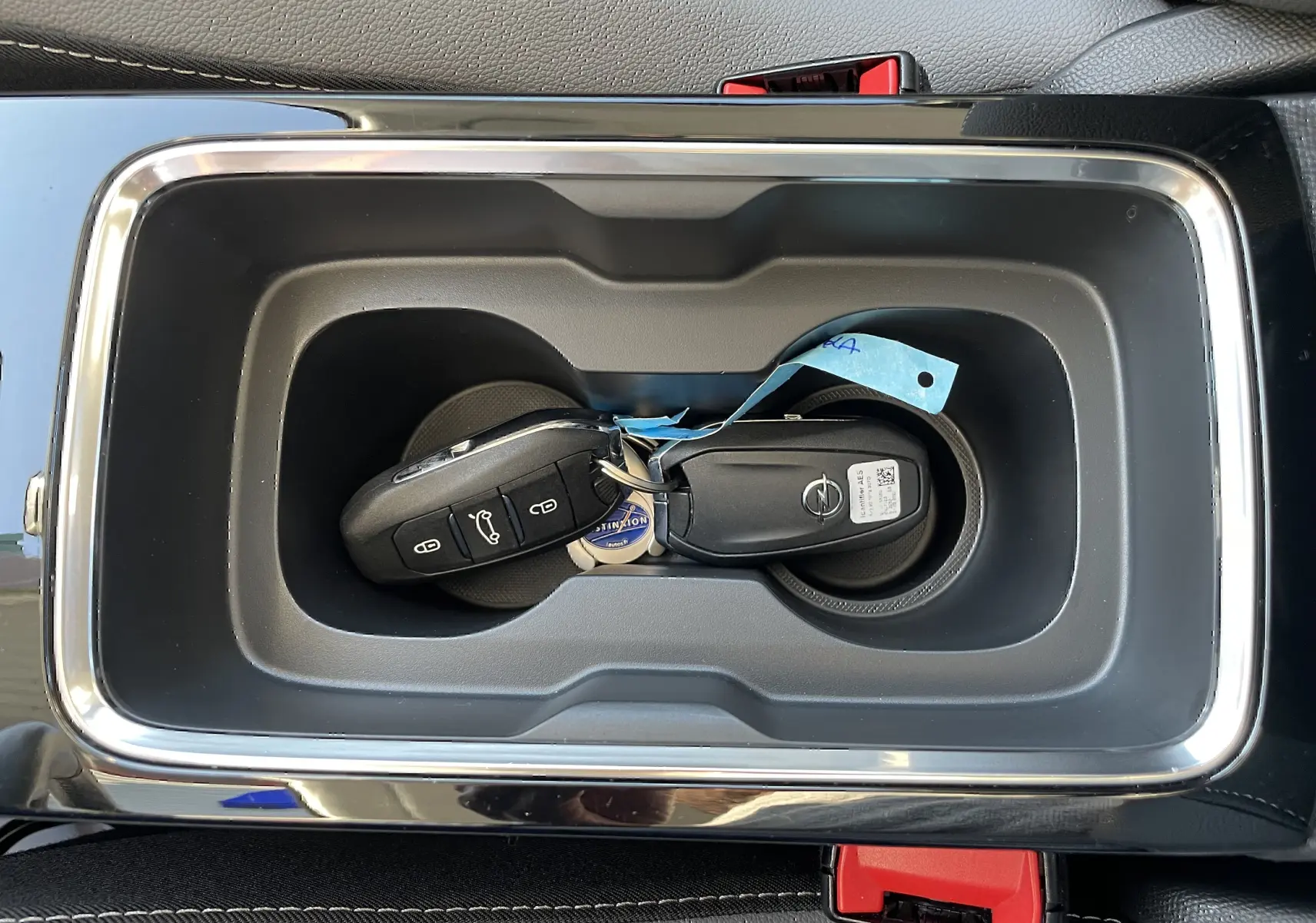Gros plan sur la clé Opel Mokka posée dans le rangement central noir avec contour chromé de la console.