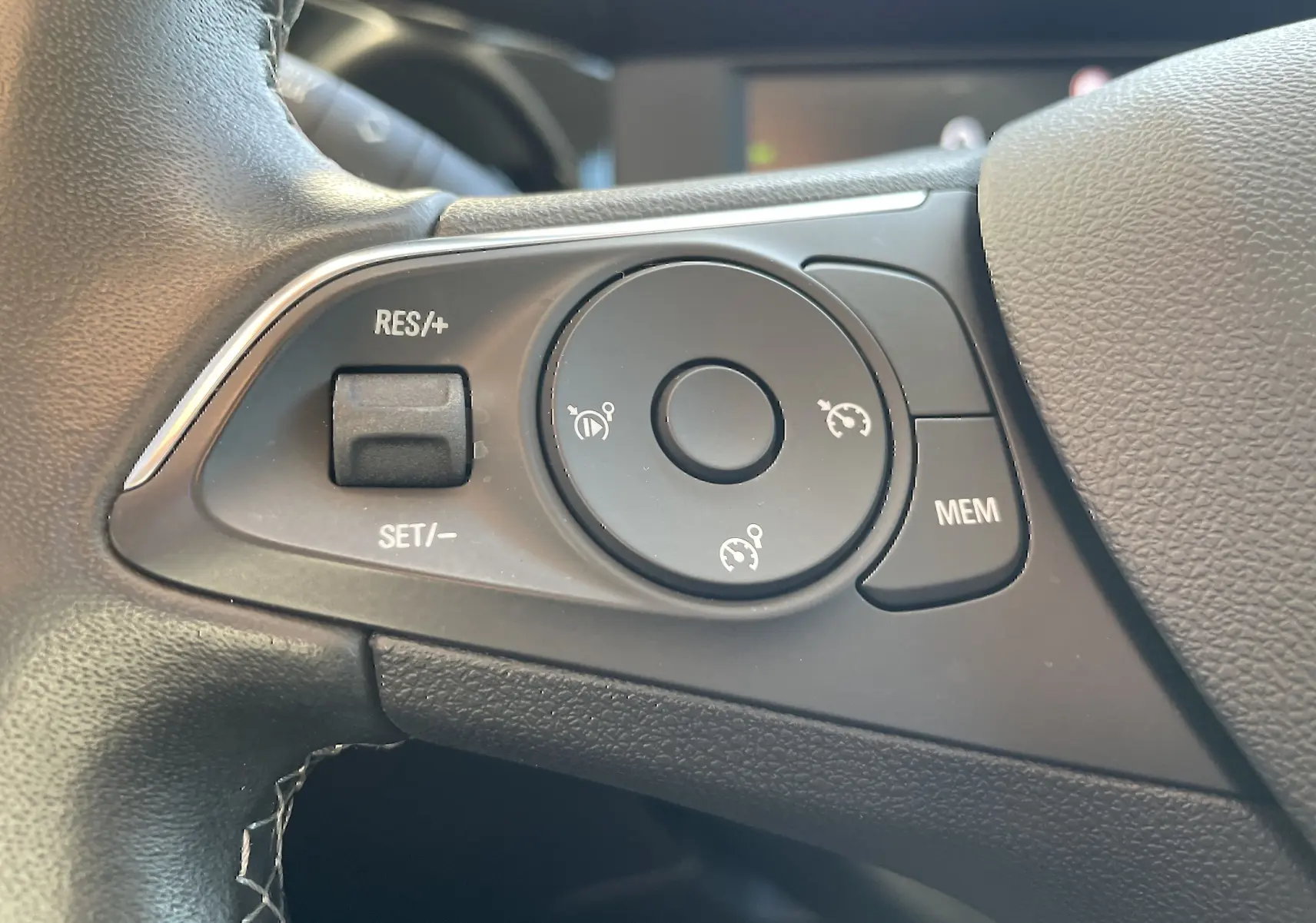 Gros plan sur les commandes de régulateur de vitesse au volant d'une Opel Mokka 2023, intérieur gris noir.