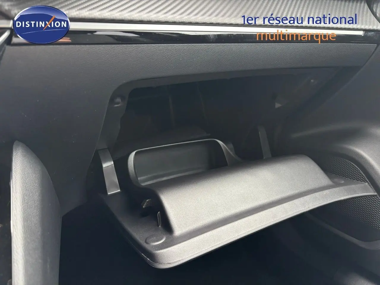Gros plan sur la boîte à gants ouverte de la Peugeot 2008 Hybrid 136ch Allure, intérieur noir moderne.