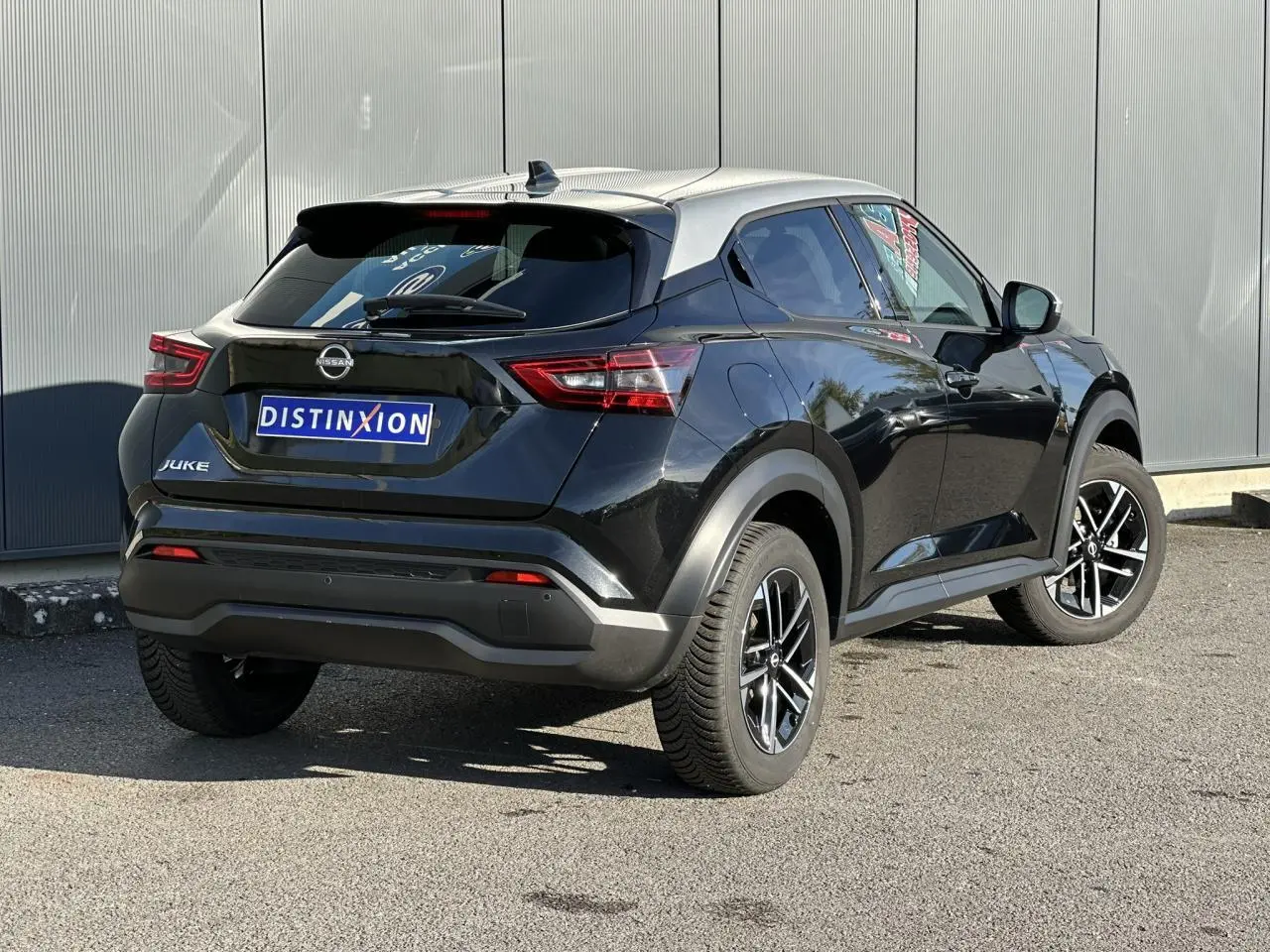 Nissan Juke noir vue 3/4 arrière droit, avec toit contrasté gris et jantes alliage 17 pouces.