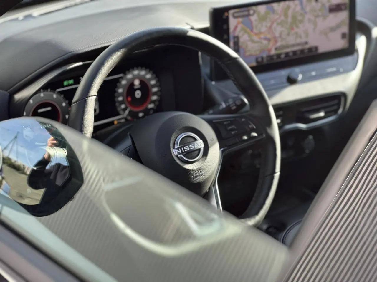 Vue rapprochée de l'intérieur du Nissan Juke 2025, volant en cuir noir avec tableau de bord digital et écran tactile GPS.