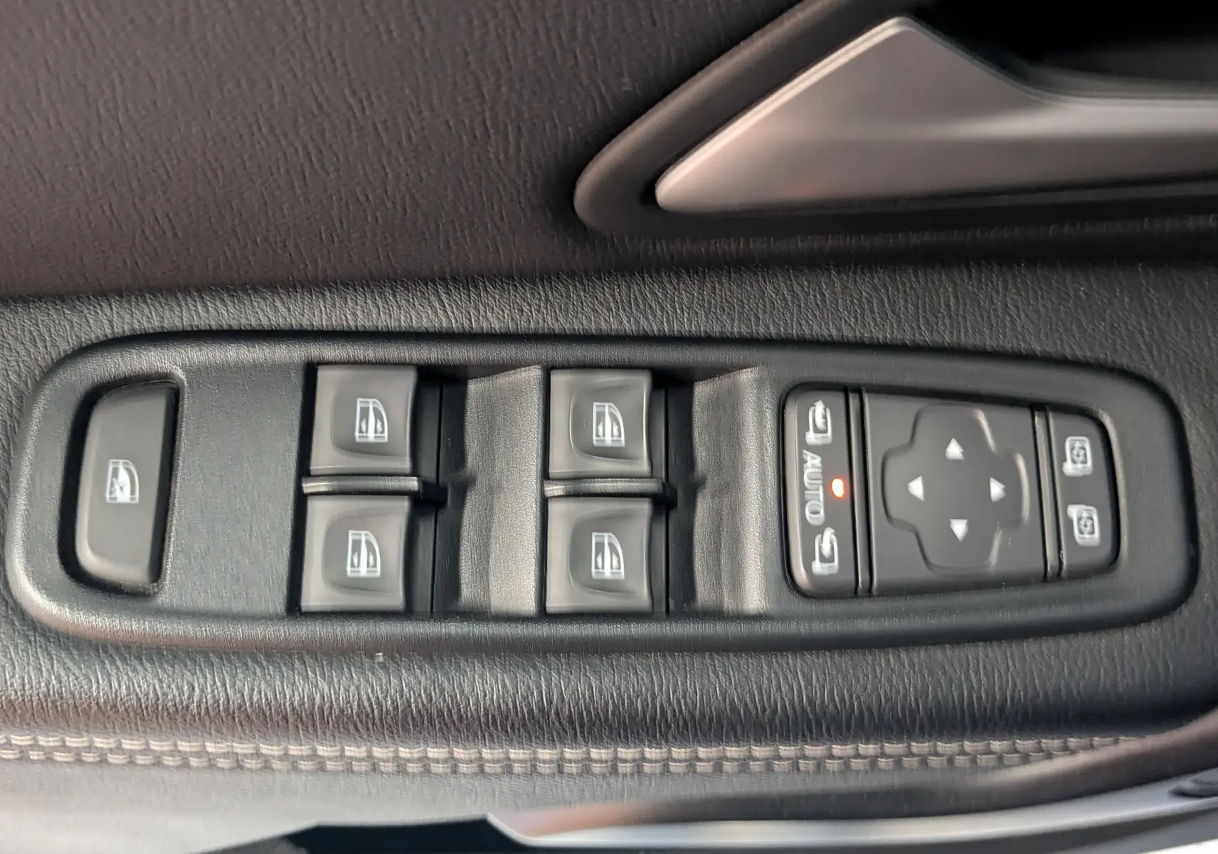 Commande des vitres électriques et réglages des rétroviseurs sur la porte côté conducteur du Dacia Duster gris 2023.