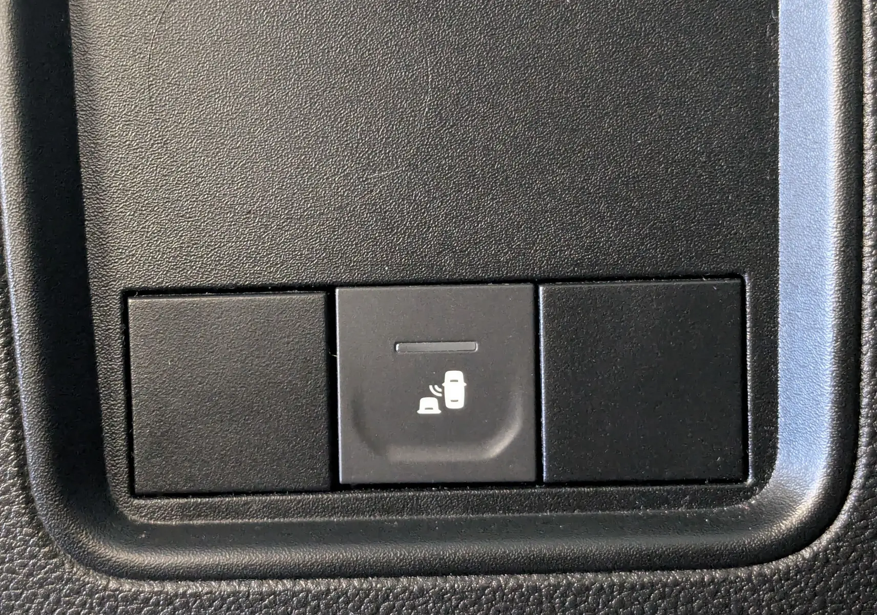 Gros plan sur le bouton d'alerte de détection d'angle mort dans l'habitacle du Dacia Duster gris 2023.