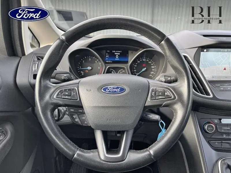 Vue intérieure centrée sur le volant cuir multifonction de la Ford C-MAX 2018 avec tableau de bord et écran tactile visibles.