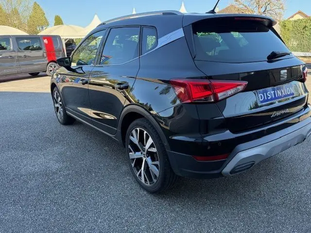 Vue 3/4 arrière droite d’un SEAT Arona noir avec toit gris, jantes alliage 18 pouces et feux arrière LED.
