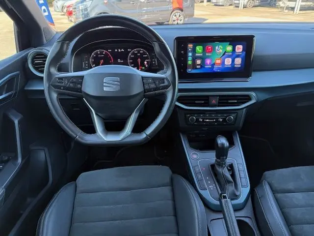 Vue intérieure avant du SEAT Arona noir avec volant multifonction, écran tactile central et sellerie en suédine noire.