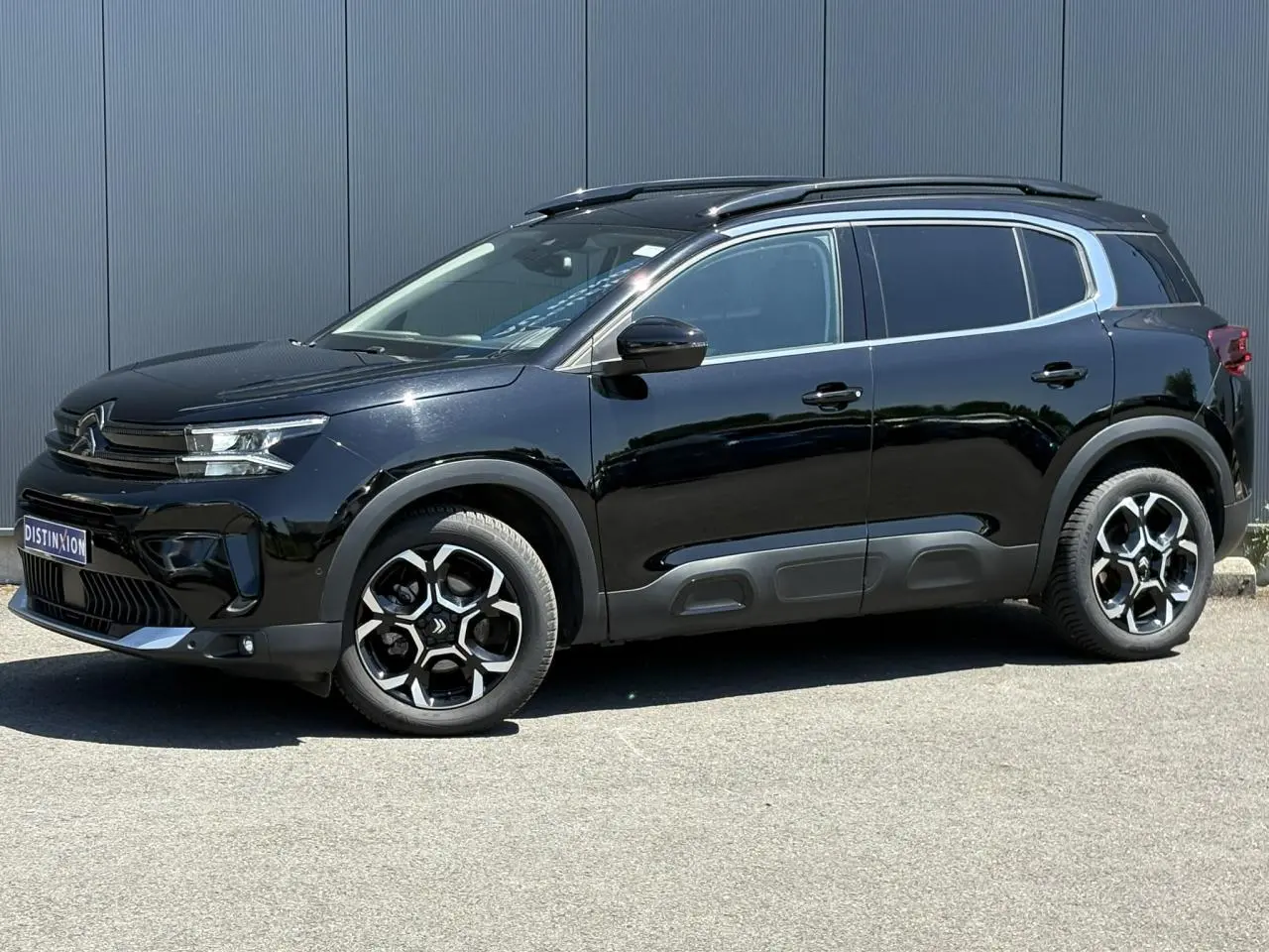 Vue latérale gauche d'un Citroën C5 Aircross Hybrid noir Perla avec jantes alliage bi-ton et barres de toit noires.
