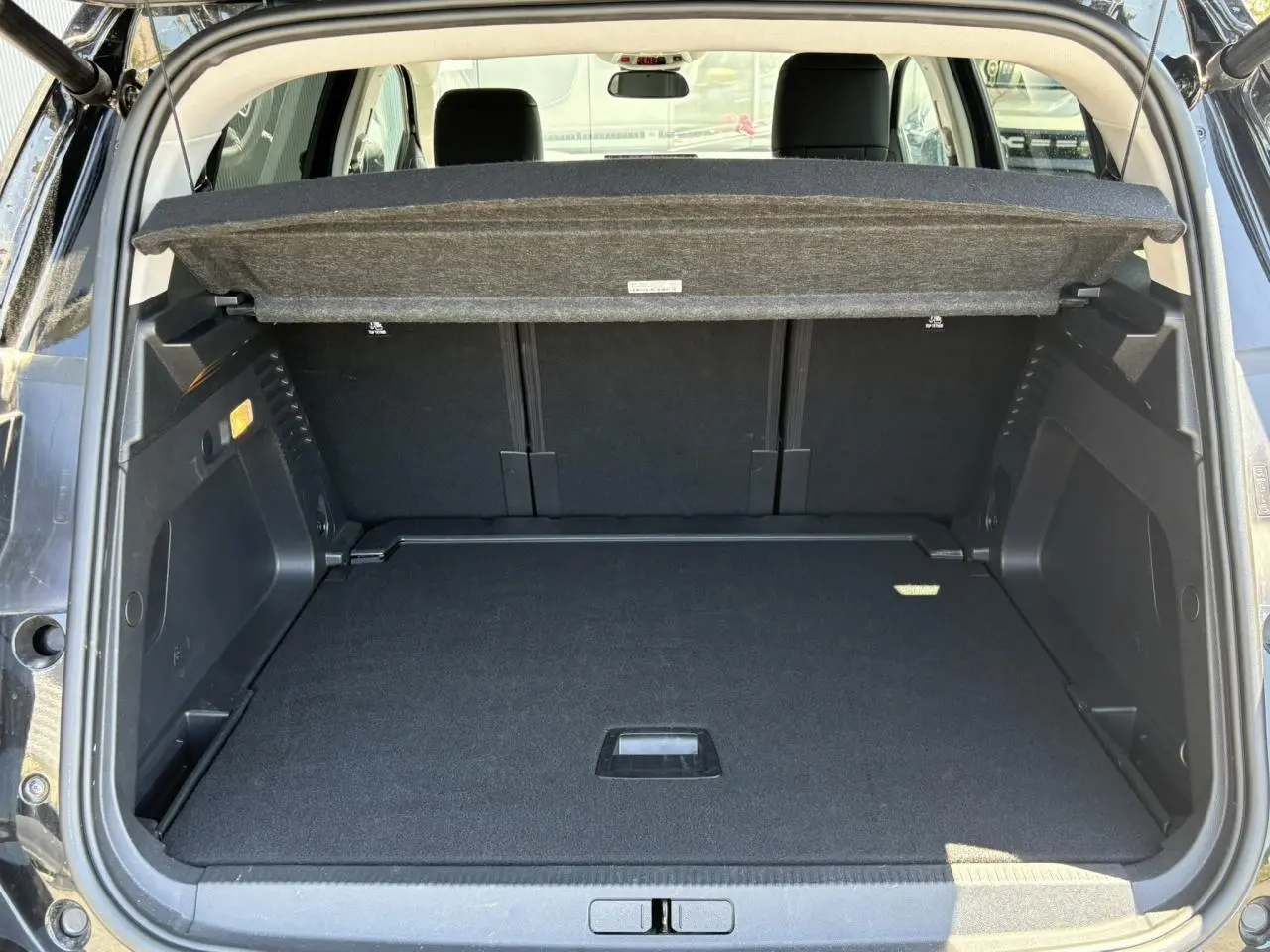 Coffre ouvert vu de l'arrière du Citroën C5 Aircross Hybrid noir Perla, avec cache-bagages relevé et espace de rangement visible.