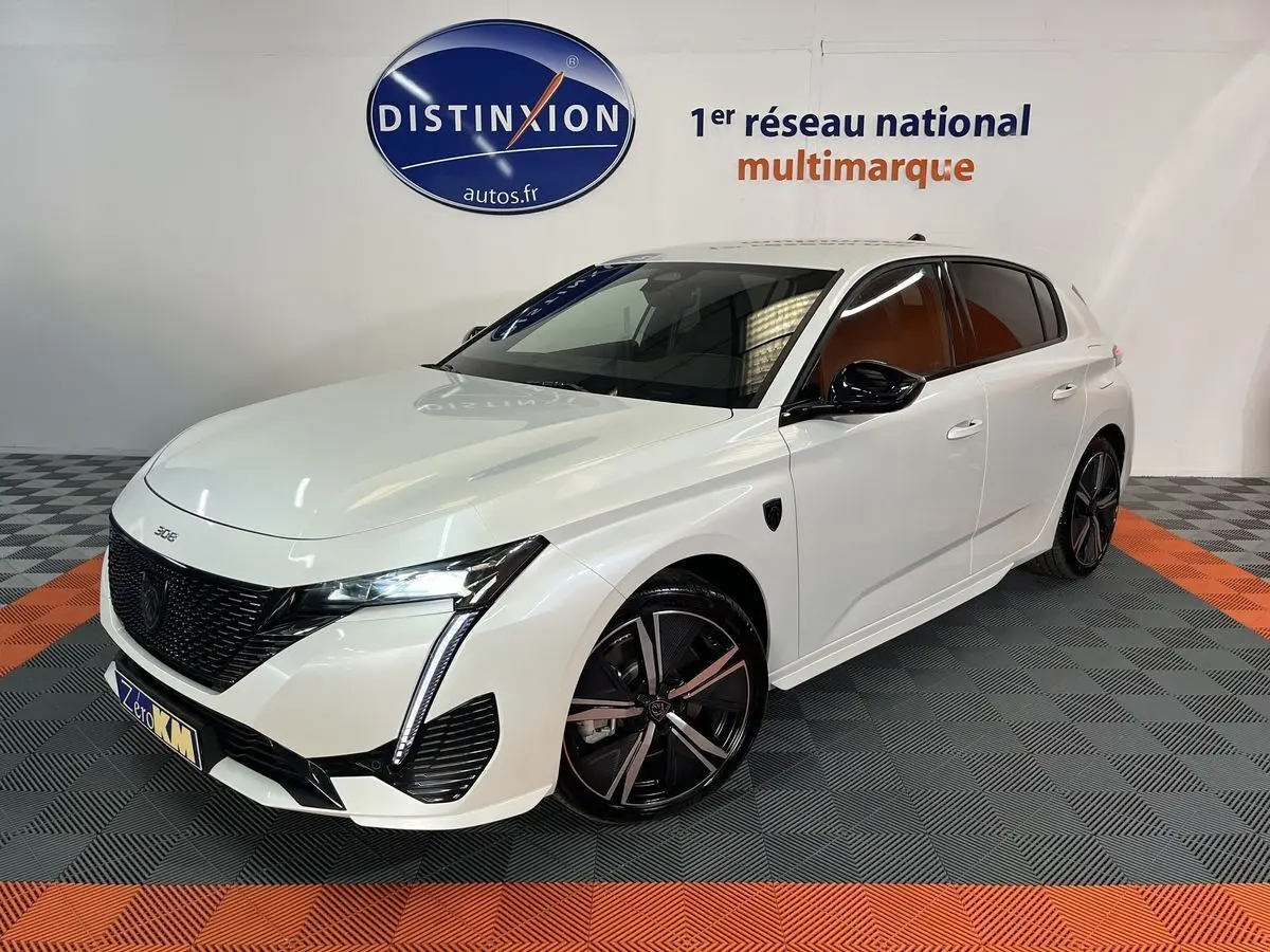 Peugeot 308 GT PHEV blanc nacré vue 3/4 avant droit avec jantes noires et détails noirs brillants.