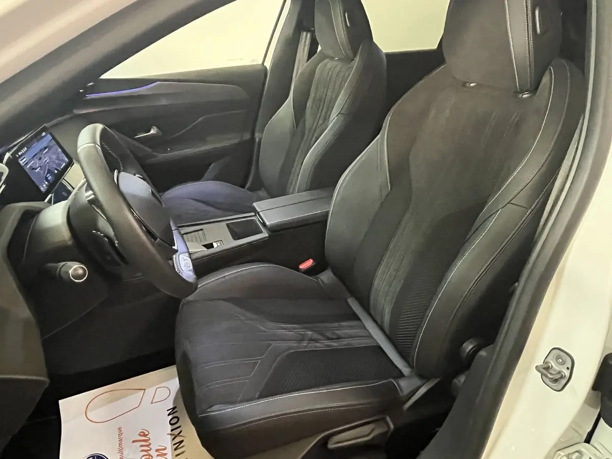 Vue intérieure côté conducteur de la Peugeot 308 GT PHEV 180 blanche avec sièges sport noirs et écran tactile.
