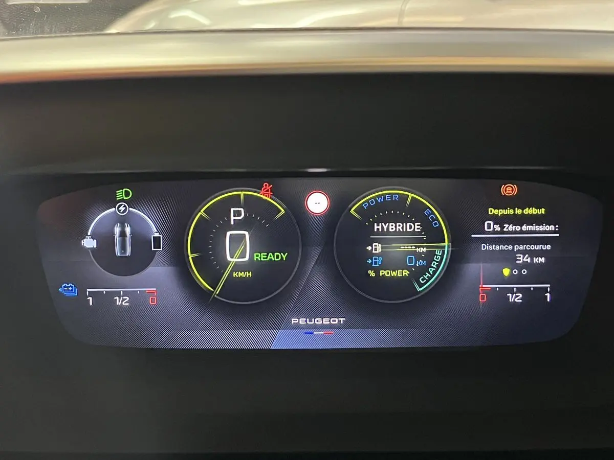 Tableau de bord numérique de la Peugeot 308 GT PHEV blanc nacré, affichant l'état hybride et la vitesse à zéro.