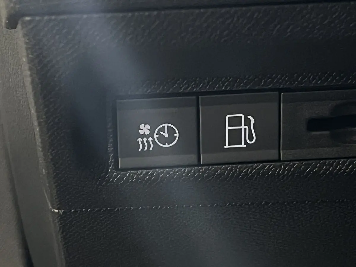 Gros plan sur les boutons de commande du chauffage et du carburant dans l'habitacle noir d'une Peugeot 308 GT PHEV blanc nacré.
