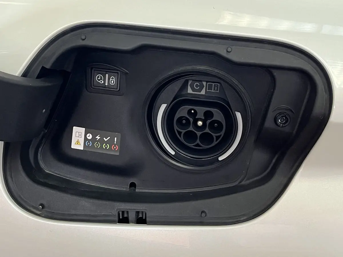 Prise de recharge hybride ouverte sur la carrosserie blanc nacré d'une Peugeot 308 GT PHEV 2022.