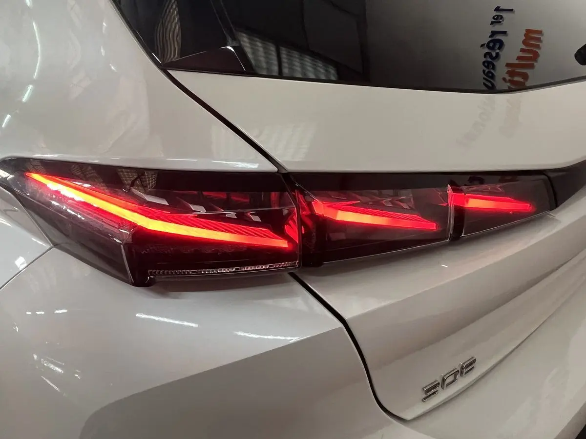 Gros plan sur le feu arrière droit rouge vif d'une Peugeot 308 GT PHEV blanc nacré, vue arrière détaillée.