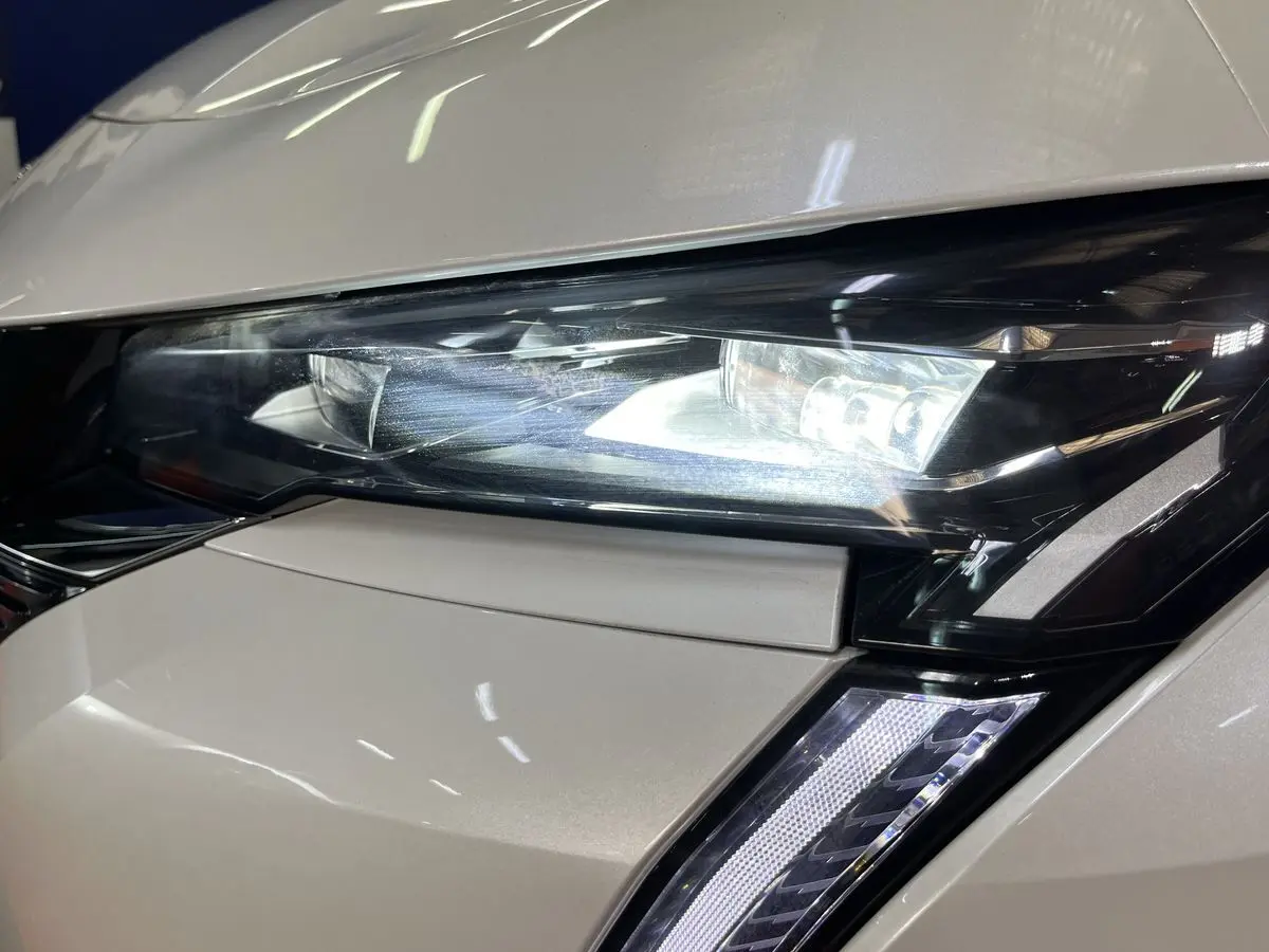 Gros plan sur le phare avant droit blanc nacré du Peugeot 308 GT PHEV 180 Hybride Rechargeable 2022 avec éclairage LED distinctif.