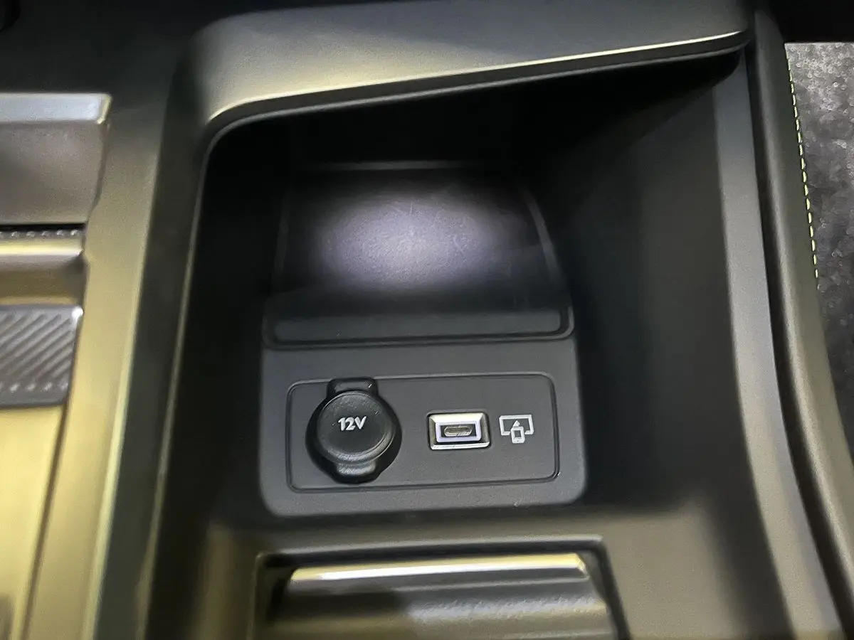 Prise 12V et port USB en gros plan dans la console centrale de la Peugeot 308 GT PHEV blanc nacré.