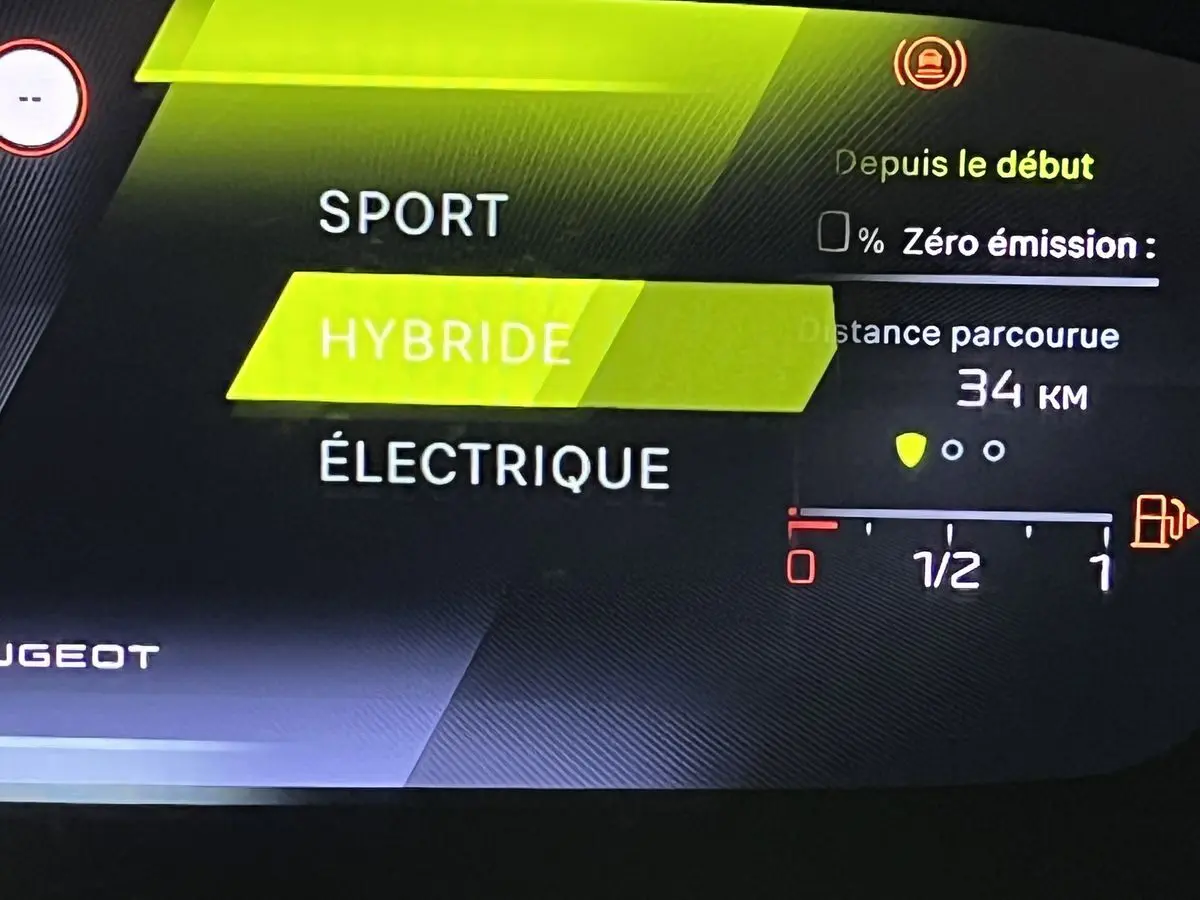 Affichage numérique intérieur de la Peugeot 308 GT PHEV 180 blanc nacré montrant le mode hybride en surbrillance.