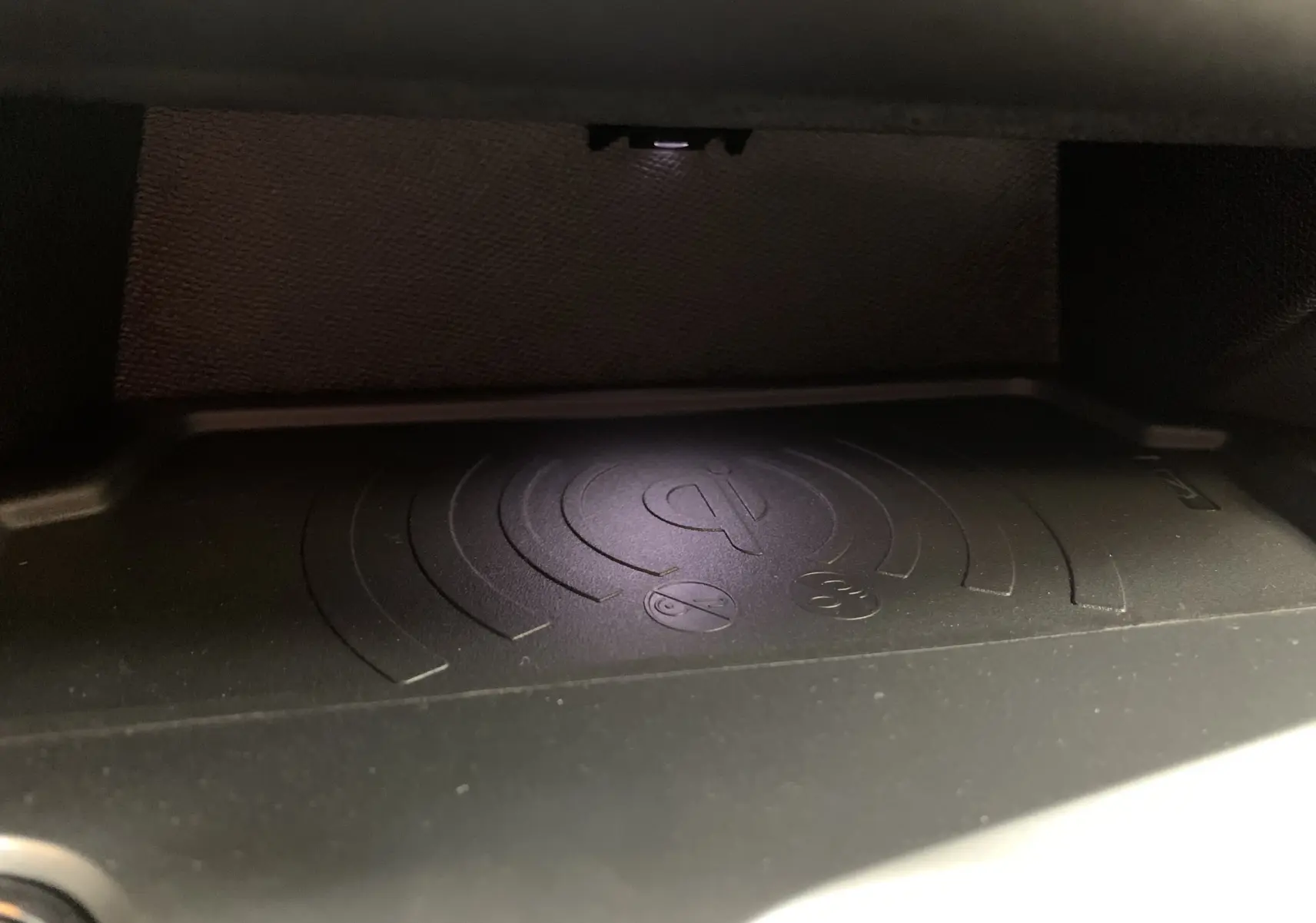 Gros plan sur le chargeur sans fil Qi intégré dans la console centrale de la Peugeot 308 GT PHEV 2022.