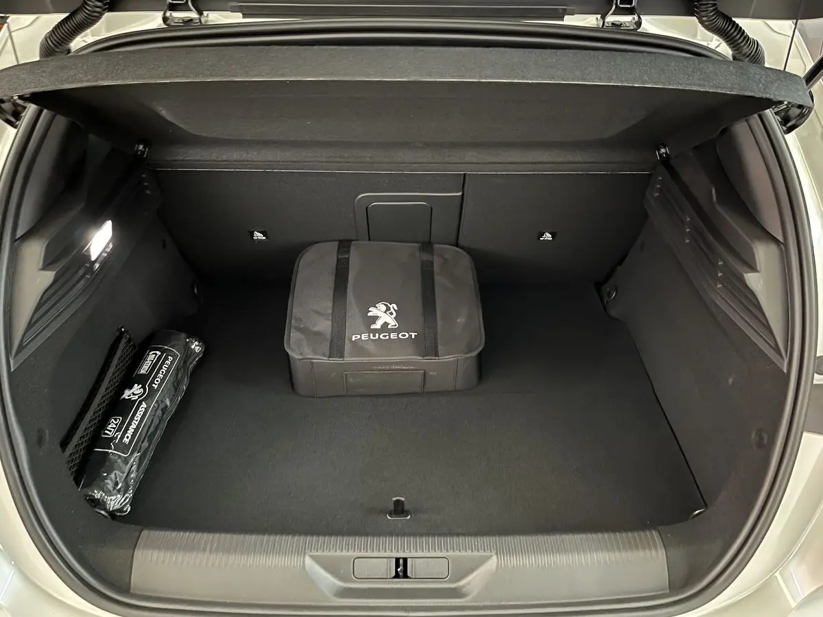 Coffre ouvert vu de l'arrière d'une Peugeot 308 GT PHEV blanc nacré avec sacoche et kit d'assistance Peugeot.
