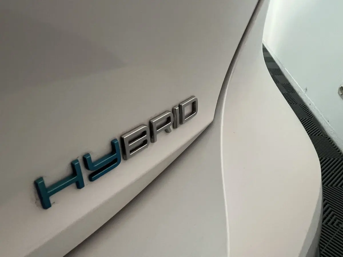 Gros plan sur l’inscription HYBRID bleue sur la carrosserie blanc nacré arrière droite d’une Peugeot 308 GT PHEV.