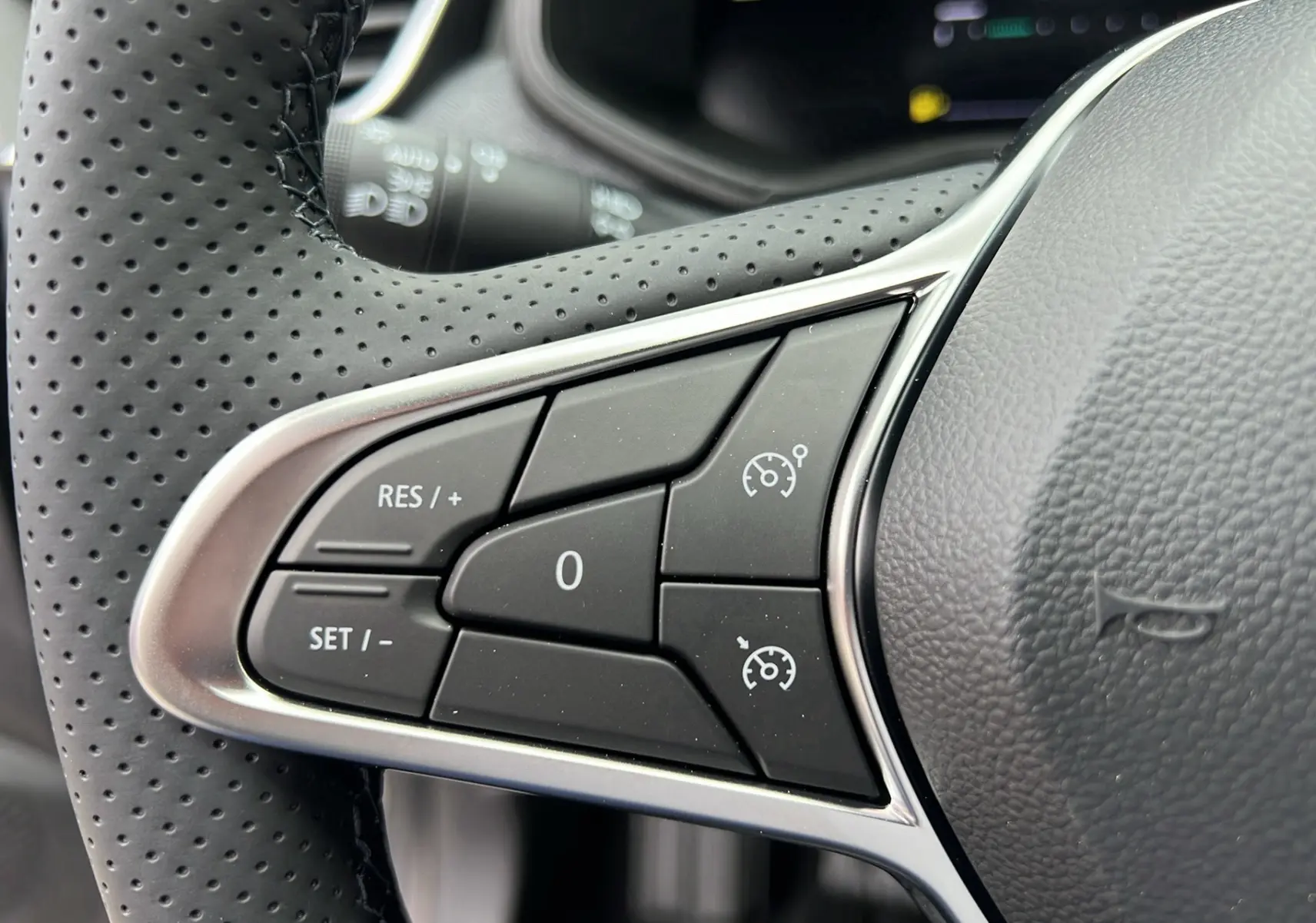 Gros plan sur les commandes de régulateur de vitesse au volant en cuir perforé de la Renault Clio V TCe 90 Techno gris schiste 2025.