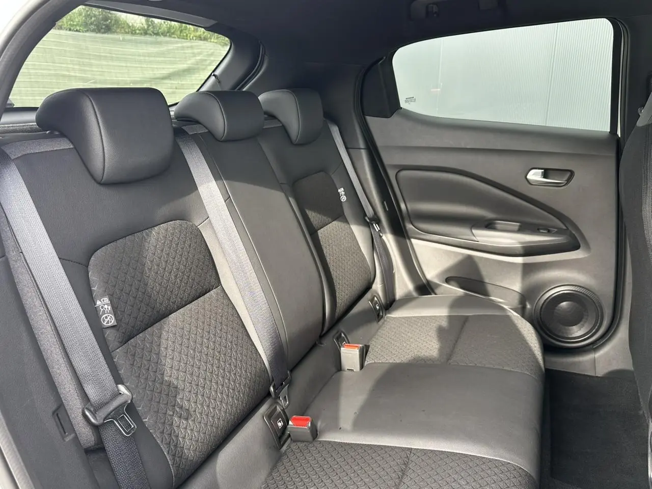 Vue intérieure côté droit des sièges arrière noirs du Nissan Juke 2025 avec garnitures en tissu et cuir.