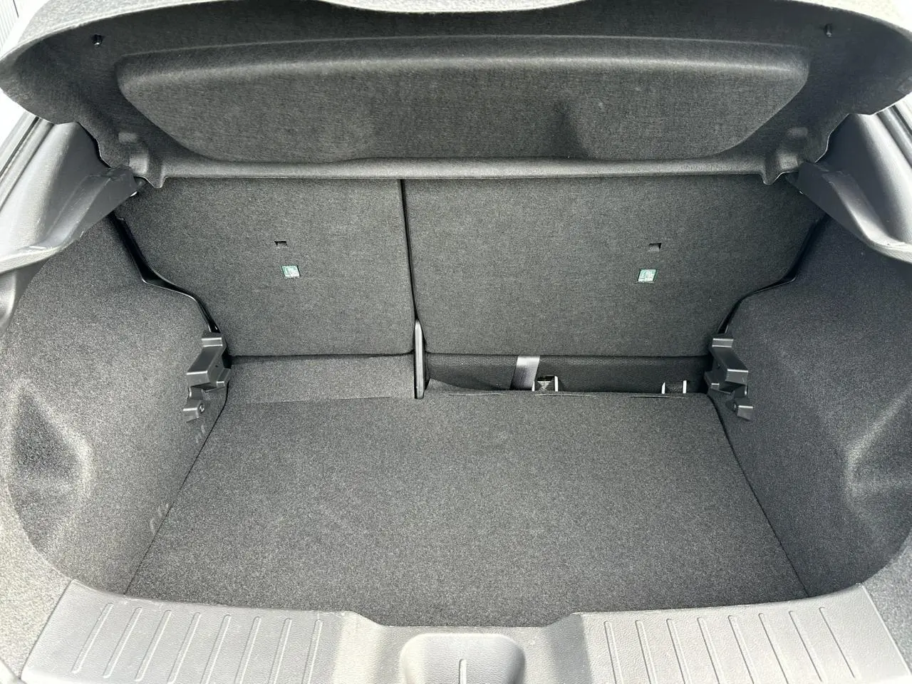 Coffre ouvert du Nissan Juke blanc nacré 2025, montrant l'espace de chargement et la banquette arrière rabattable.