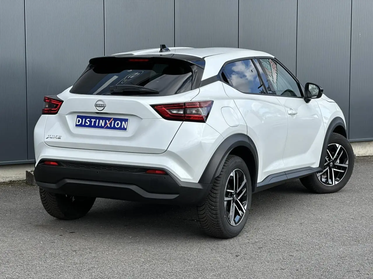Vue 3/4 arrière droit d'un Nissan Juke blanc nacré avec jantes alliage noires et vitres teintées.