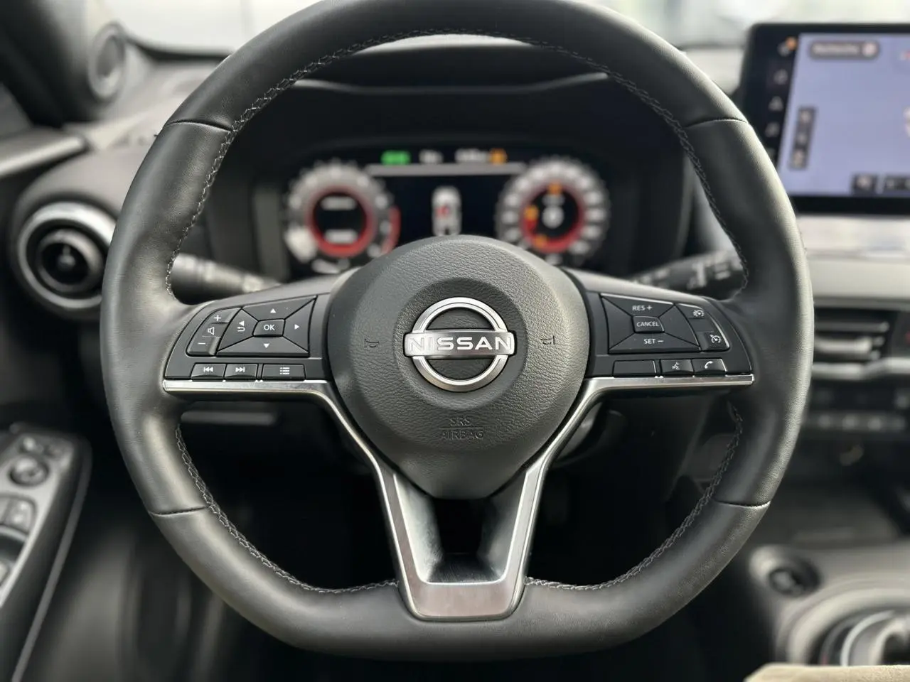 Volant en cuir noir de Nissan Juke 2025 avec commandes intégrées et tableau de bord digital en arrière-plan.