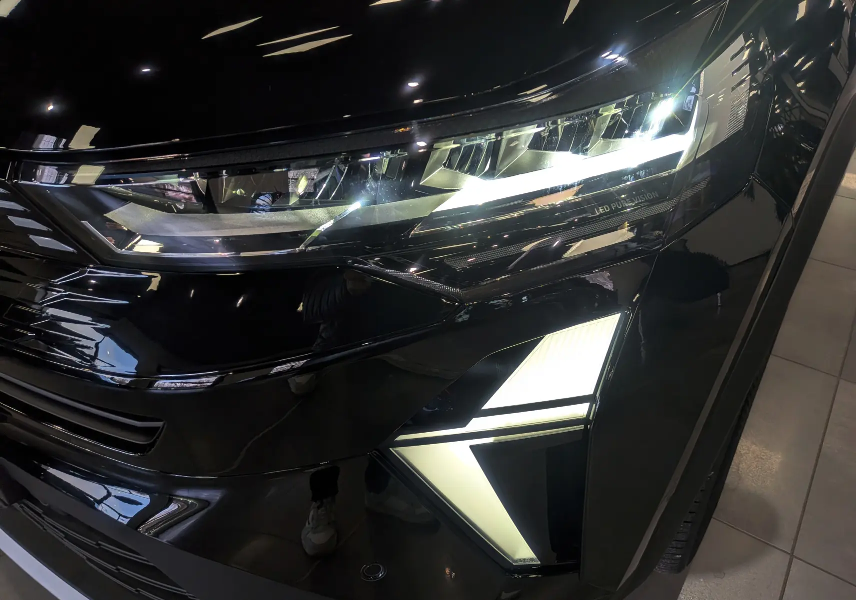 Gros plan sur le phare avant droit noir étoilé du Renault SYMBIOZ E-Tech full hybrid 160 ch Iconic avec éclairage LED distinctif.