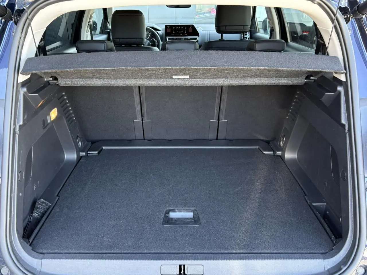 Vue arrière du coffre ouvert du Citroën C5 Aircross Hybrid bleu Eclipse, montrant l'espace de chargement et la plage arrière.