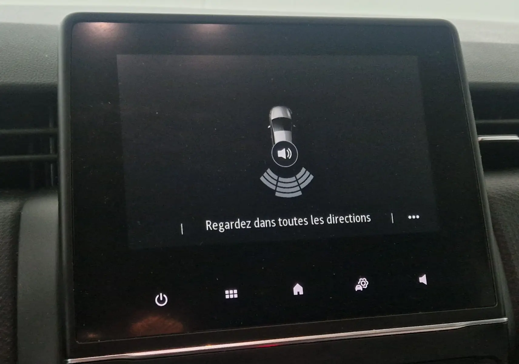 Écran tactile de la Renault Clio V gris platine affichant l'alerte de détection d'obstacles avec message "Regardez dans toutes les directions"