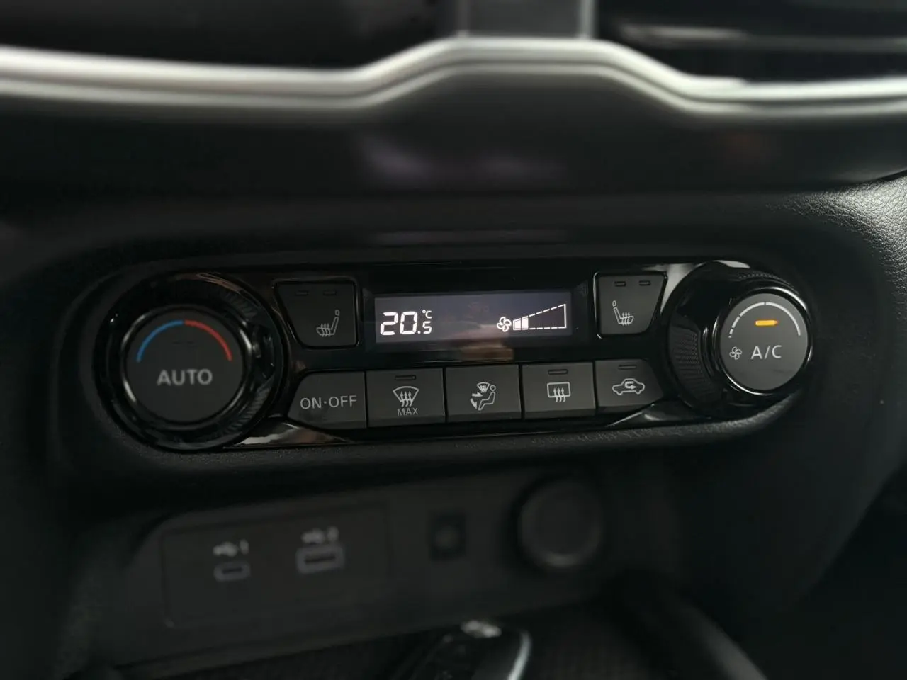 Gros plan sur la console de climatisation automatique du Nissan Juke blanc nacré, avec affichage digital et commandes tactiles.
