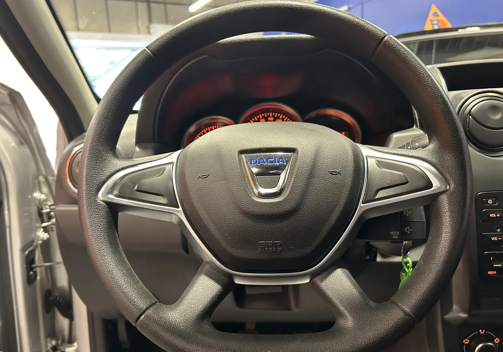 Volant noir avec logo Dacia au centre, vue frontale de l'intérieur du Dacia Duster gris 2017 avec tableau de bord visible.