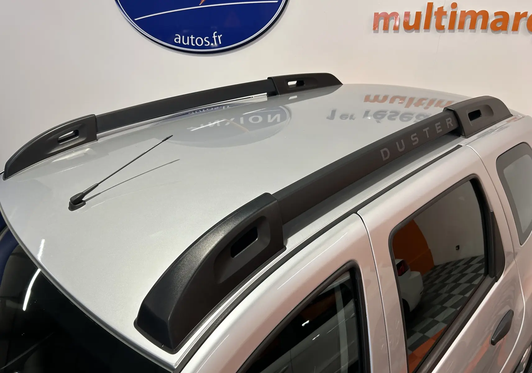 Vue rapprochée du toit gris clair du Dacia Duster 2017 avec barres de toit noires marquées DUSTER.