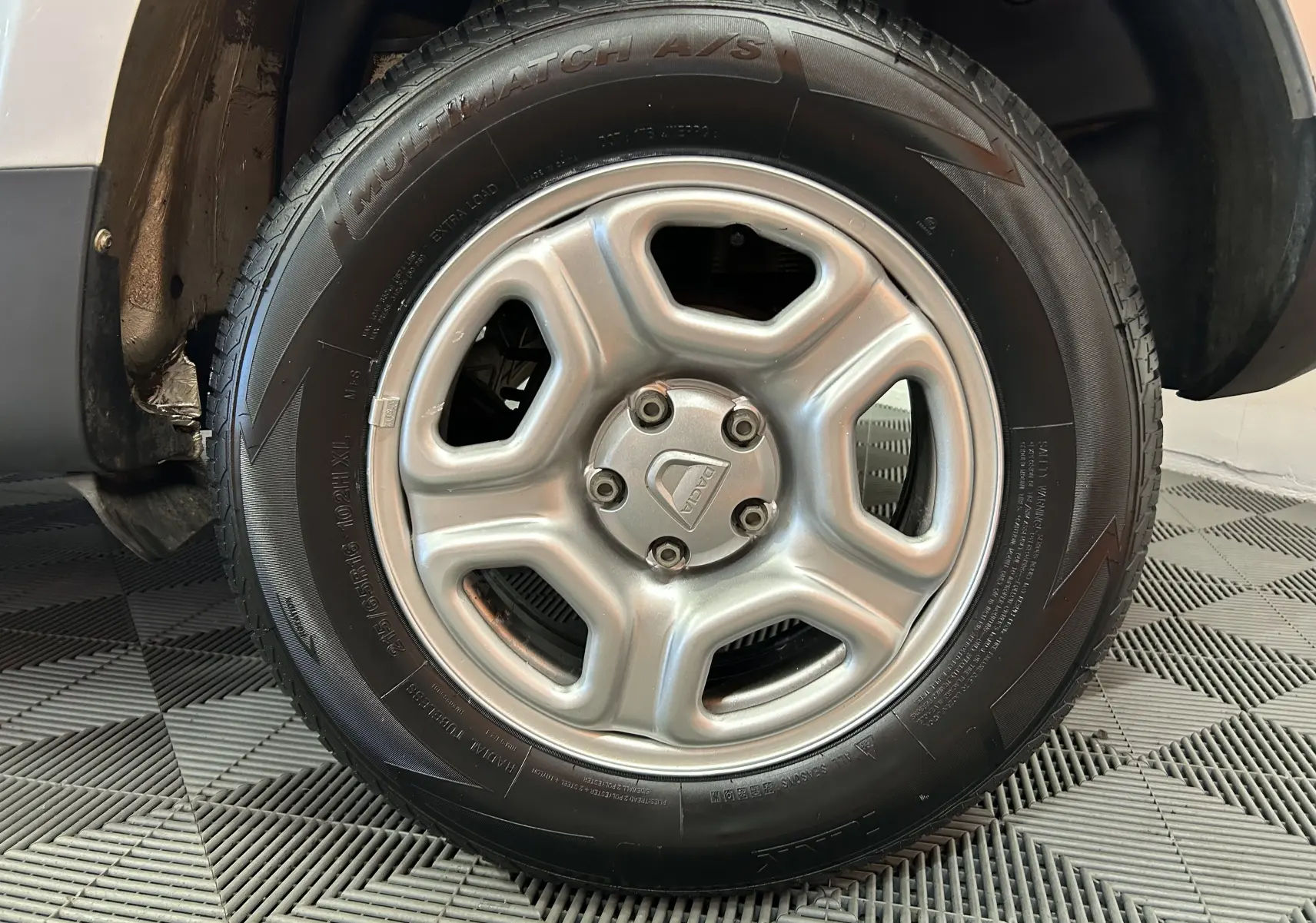 Gros plan sur la roue avant gauche grise du Dacia Duster 2017 avec jante acier et logo central visible.