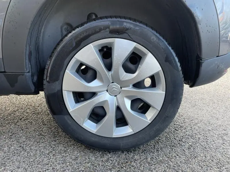 Gros plan sur la roue avant droite d'une Citroën C4 Cactus gris foncé métal de 2019 avec jante en alliage distinctive.