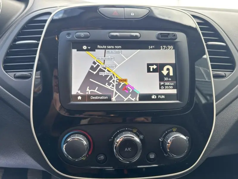 Vue rapprochée de l’écran tactile GPS et des commandes de climatisation du tableau de bord noir du Renault Captur gris platine 2019.