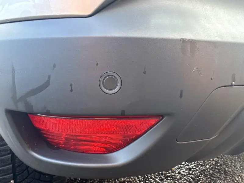 Gros plan sur le pare-chocs arrière gris platine du Renault Captur 2019 avec feu antibrouillard rouge et capteur de recul.