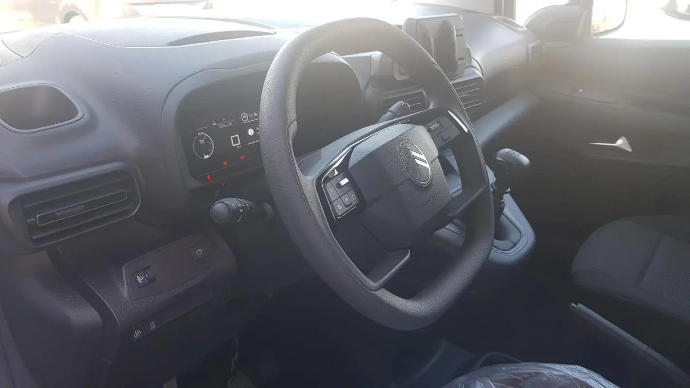 Vue intérieure du poste de conduite du Citroën Berlingo 2025, volant multifonctions et levier de vitesse manuel visibles.