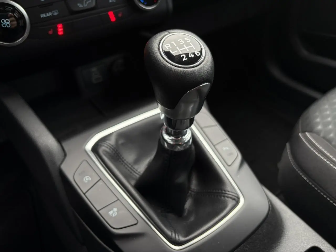 Gros plan sur le levier de vitesses manuel du Ford Kuga 2024, avec console centrale et sellerie noire visible.