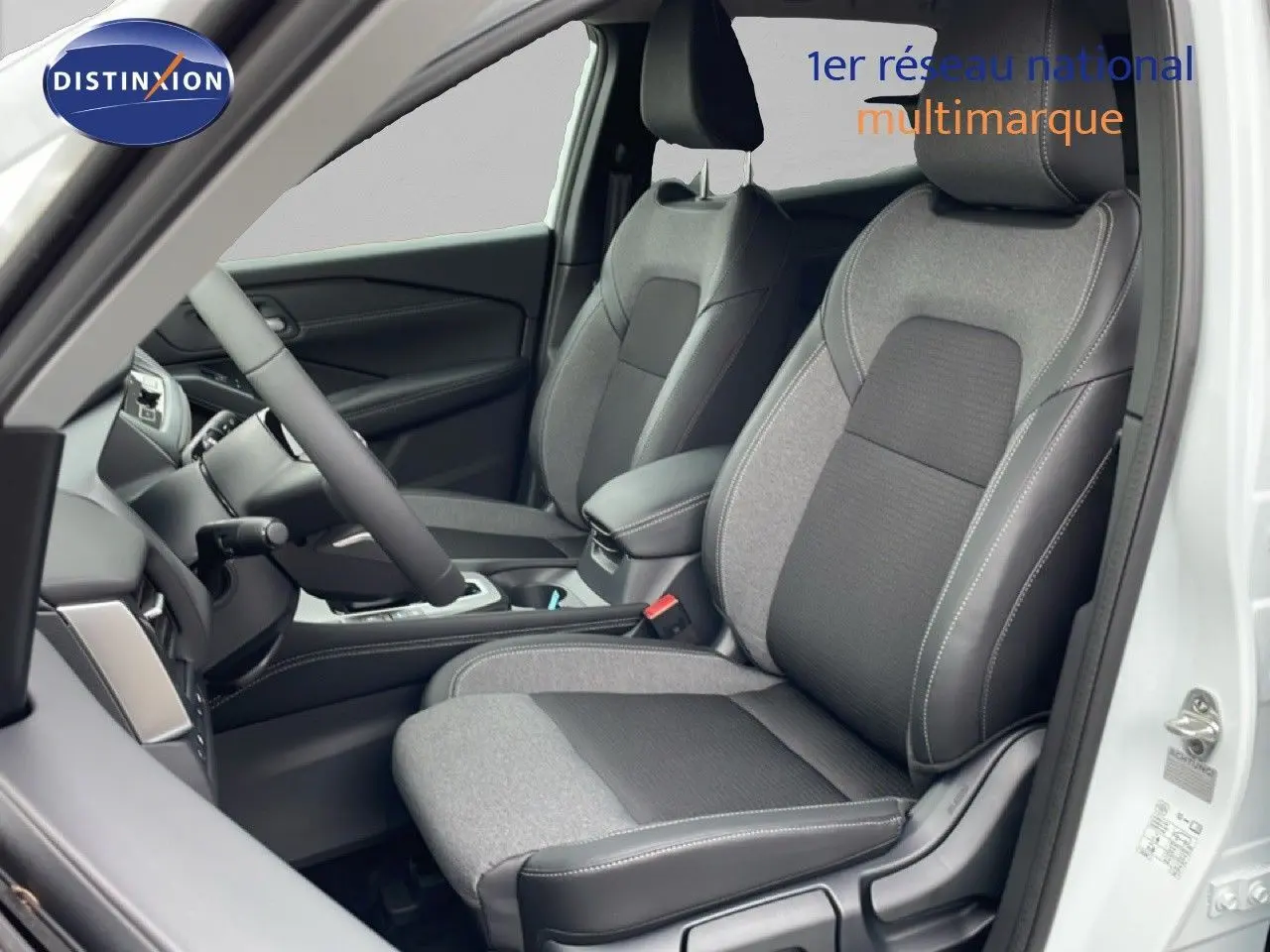 Vue intérieure côté conducteur du Nissan Qashqai blanc nacré, mettant en valeur les sièges bi-matière gris et noir.