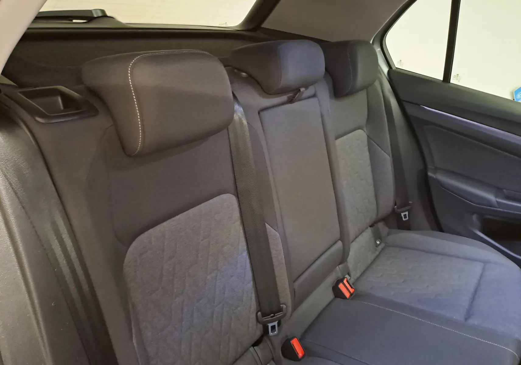 Vue intérieure des sièges arrière en tissu gris avec appuie-têtes et ceintures de sécurité de la Volkswagen Golf 2025.