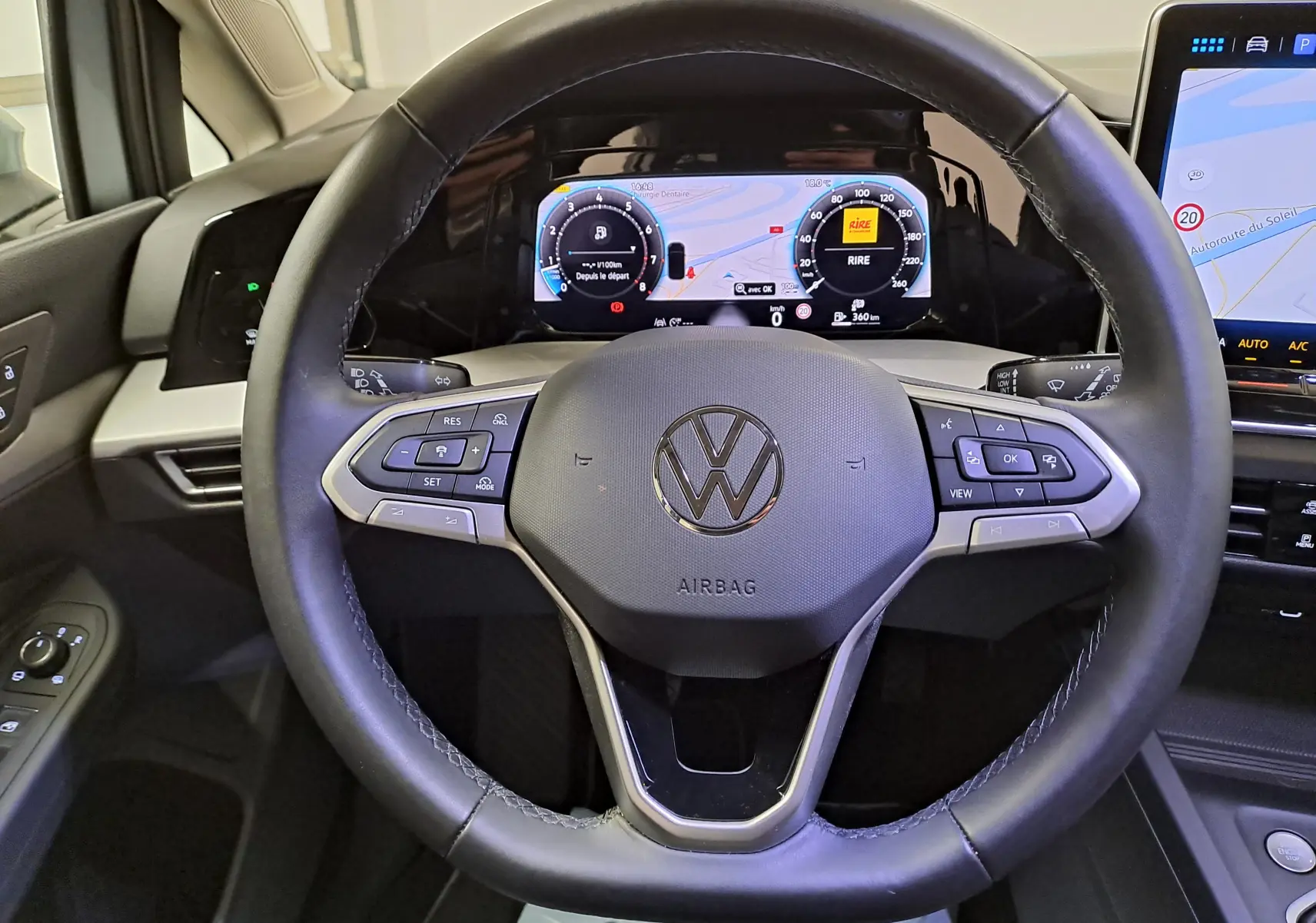 Vue intérieure centrée sur le volant noir de la Volkswagen Golf 1.5 eTSI 2025 avec tableau de bord numérique allumé.